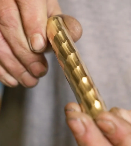 Blacksmith holding length of rolled & hammered texture